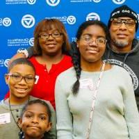 A family poses for a group photo in front of the GVSU backdrop